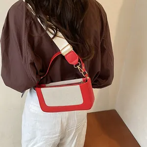 Detail view of the red leather and canvas patchwork bag with adjustable wide strap