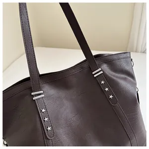 Detail of dark brown tote bag with star rivets and litchi grain leather texture