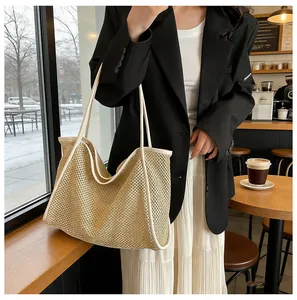 Detail view of woven straw tote bag with white leather straps in a cafe setting