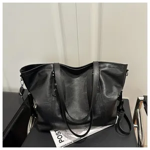 Detail of black leather tote bag with star rivets and adjustable strap on a chair