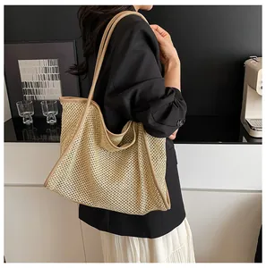 Side view of a large woven straw tote bag with brown leather straps worn by a model