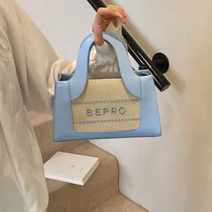 Detailopname van het BEPRO-borduurwerk op de blauwe leren en geweven crossbodytas
