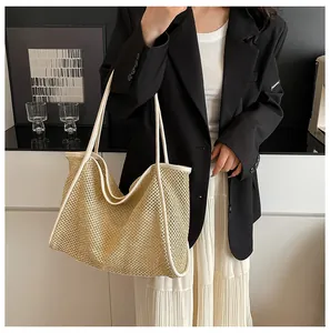 Detail view of woven straw tote bag with beige trim worn by a model in a minimalist setting