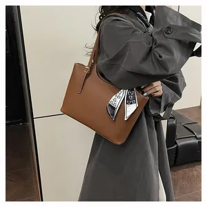 Detail showing brown lychee textured leather tote bag with elegant silk scarf accent