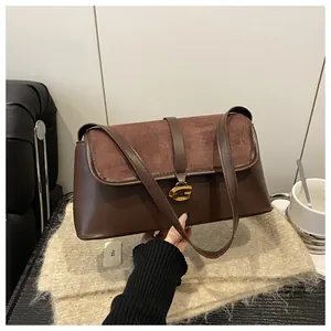 Close-up of brown patchwork baguette bag with gold G-shaped metal buckle and suede flap