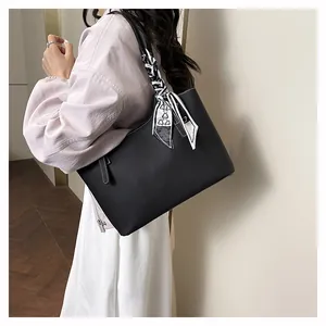 Detail of black pebbled tote bag with contrast stitching and decorative silk scarf handle
