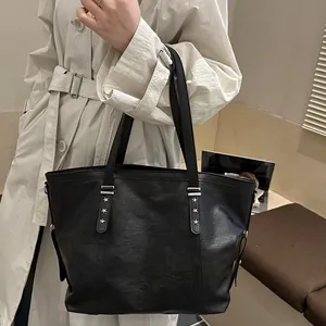 Black textured leather tote bag with silver star rivets and long shoulder straps