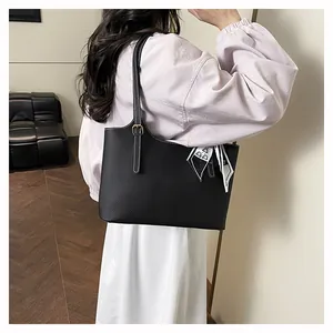 Detail of black pebbled leather tote bag with white stitching and bear silk scarf