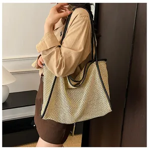 Detail of a large woven tote bag with contrast leather trim and long shoulder straps