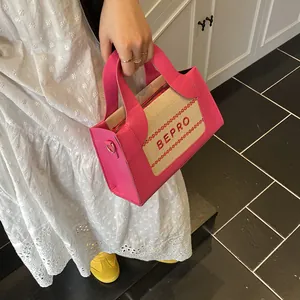 Detail van roze leer en canvas stiksels met rood BEPRO-borduurwerk op een handtas
