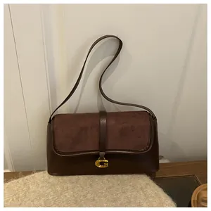 Detail of dark brown baguette bag with suede texture and golden metal buckle