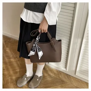 Detail of dark brown pebble leather tote bag with stylish heart print silk scarf handle