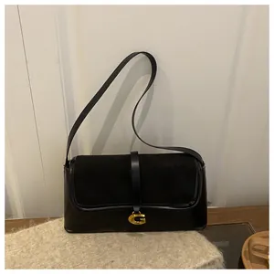 Detail of black underarm bag with gold G-shaped metal buckle and spliced leather textures