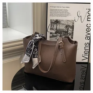 Detail of dark brown tote bag with pebbled texture and elegant silk scarf accessory