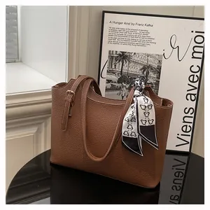 Close-up of brown litchi grain leather tote bag featuring a decorative printed silk scarf