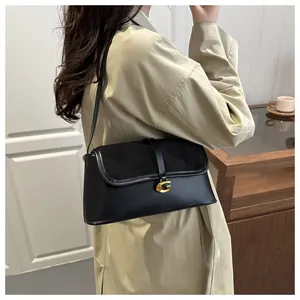 Close-up of black mixed-material shoulder bag with elegant gold G-shaped metal buckle