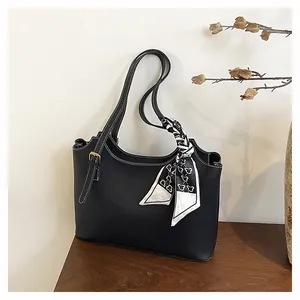 Close-up of black lychee grain leather tote bag with white stitching and silk scarf