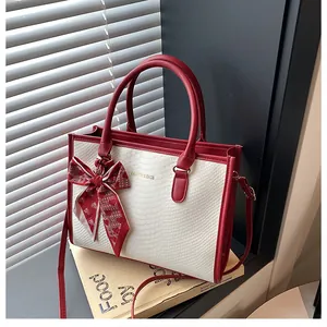 Détail du sac cabas en peau de serpent avec nœud en foulard et lettrage doré