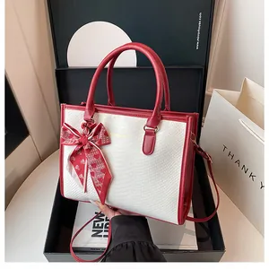 Détail du sac cabas gaufré crocodile blanc avec anses rouges et foulard à cœurs