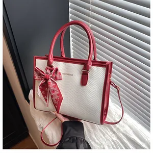 Détail du sac cabas blanc à texture croco avec foulard rouge et boucles dorées
