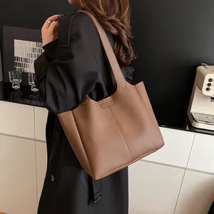 Detail of a large vintage brown leather tote bag with vertical stripes worn on shoulder