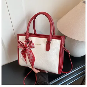 Détail du sac rouge et blanc à motif serpent avec foulard cœur et logo doré