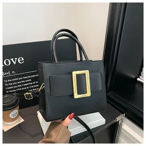 Modern black faux leather handbag with golden square buckle and adjustable shoulder strap