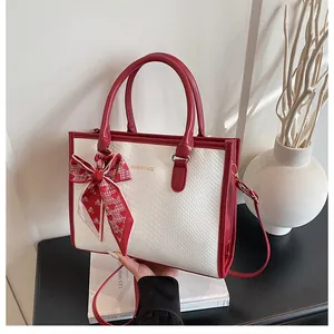 Détail du sac cabas serpent rouge et blanc avec un nœud décoratif en foulard soyeux