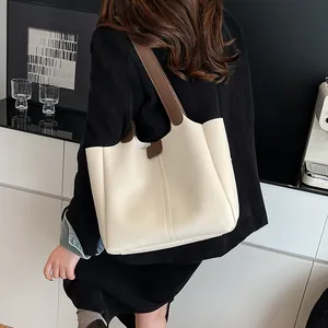 Modern minimalist off-white large tote bag with brown straps shown on a model's shoulder
