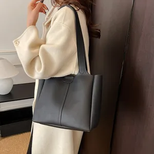Detail view of the black leather tote bag featuring sleek vertical stitching and magnetic buckle