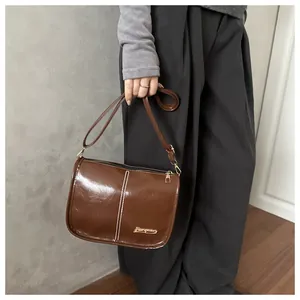 Detailansicht der braunen Boston-Tasche mit weißen Nähten und goldenem Logo-Schild