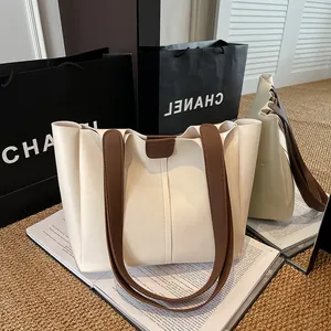 Detailed view of cream leather tote bag with brown straps on a magazine background