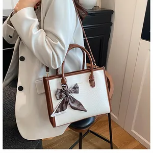 Détail du sac cabas blanc gaufré avec anses marron et foulard en soie à motif cœur