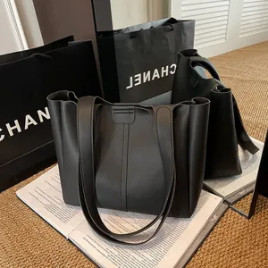 Close-up of a black matte leather tote bag showcasing its spacious interior and wide straps