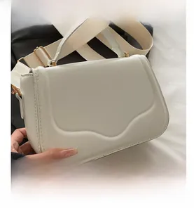 Close-up of white crossbody bag with wave texture and wide adjustable fabric strap