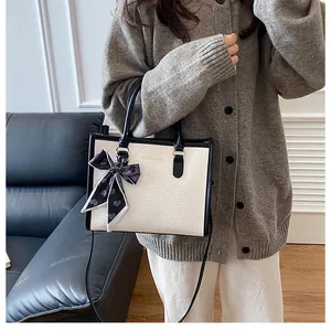 Détail de la texture crocodile avec foulard en soie et lettrage doré sur le sac à main