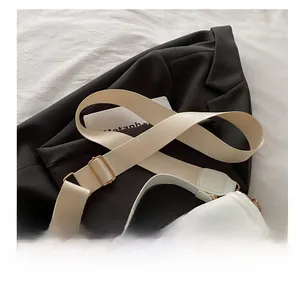 Detail of ivory faux leather handbag showing a wide woven strap with gold metal hardware