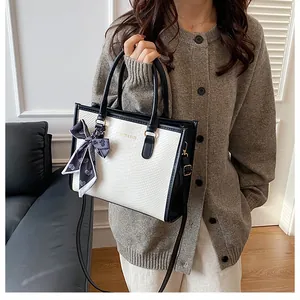 Détail du sac à main blanc motif serpent avec bordure noire et foulard en soie élégant