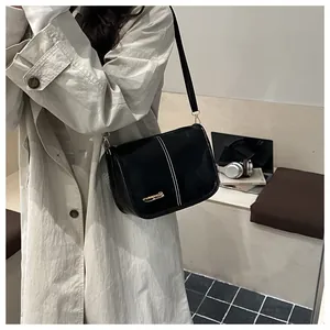 Close-up of black PU leather Boston bag featuring white stitching and gold metal logo