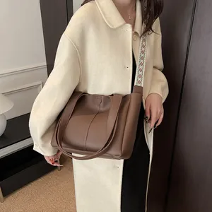 Retro brown leather tote bag with stylish bohemian woven strap shown in an outdoor setting