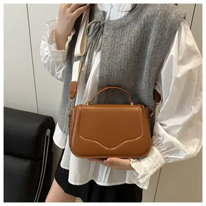 Detailed shot of a brown crossbody bag featuring wide woven strap and embossed texture