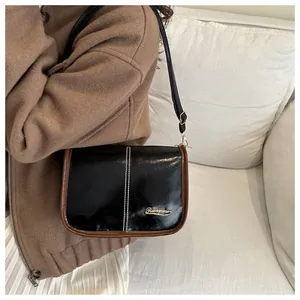 Detail of Boston bag showing glossy black leather and brown trim with golden logo