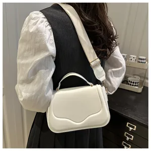Rear view of a white crossbody bag with grooved texture and a wide fabric strap