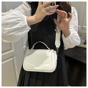Detail of cream white crossbody bag featuring a wide adjustable strap and stylish top handle