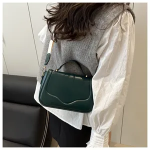 Deep green leather saddle bag with wide shoulder strap worn with casual outfit
