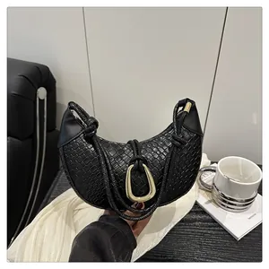 Détail du sac demi-lune noir tressé avec boucle dorée et poignée à nœud élégante