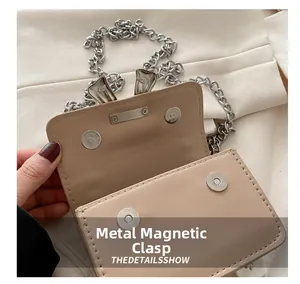 Detail of dual silver magnetic buckles and refined leather stitching on a mini bag