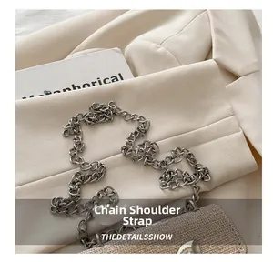 Close-up of silver metal chain strap and tweed fabric texture on a stylish mini bag
