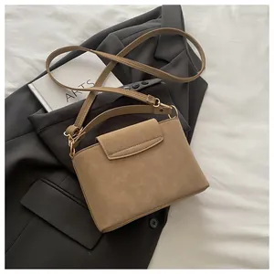Detail of dark khaki PU leather handbag with vintage texture and gold metal hardware