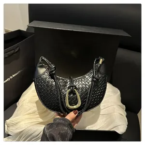 Détail du sac demi-lune tressé noir avec un grand anneau doré et une poignée nouée
